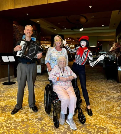 A mime with an accordion player and guests at an event, the mime in traditional whiteface costume